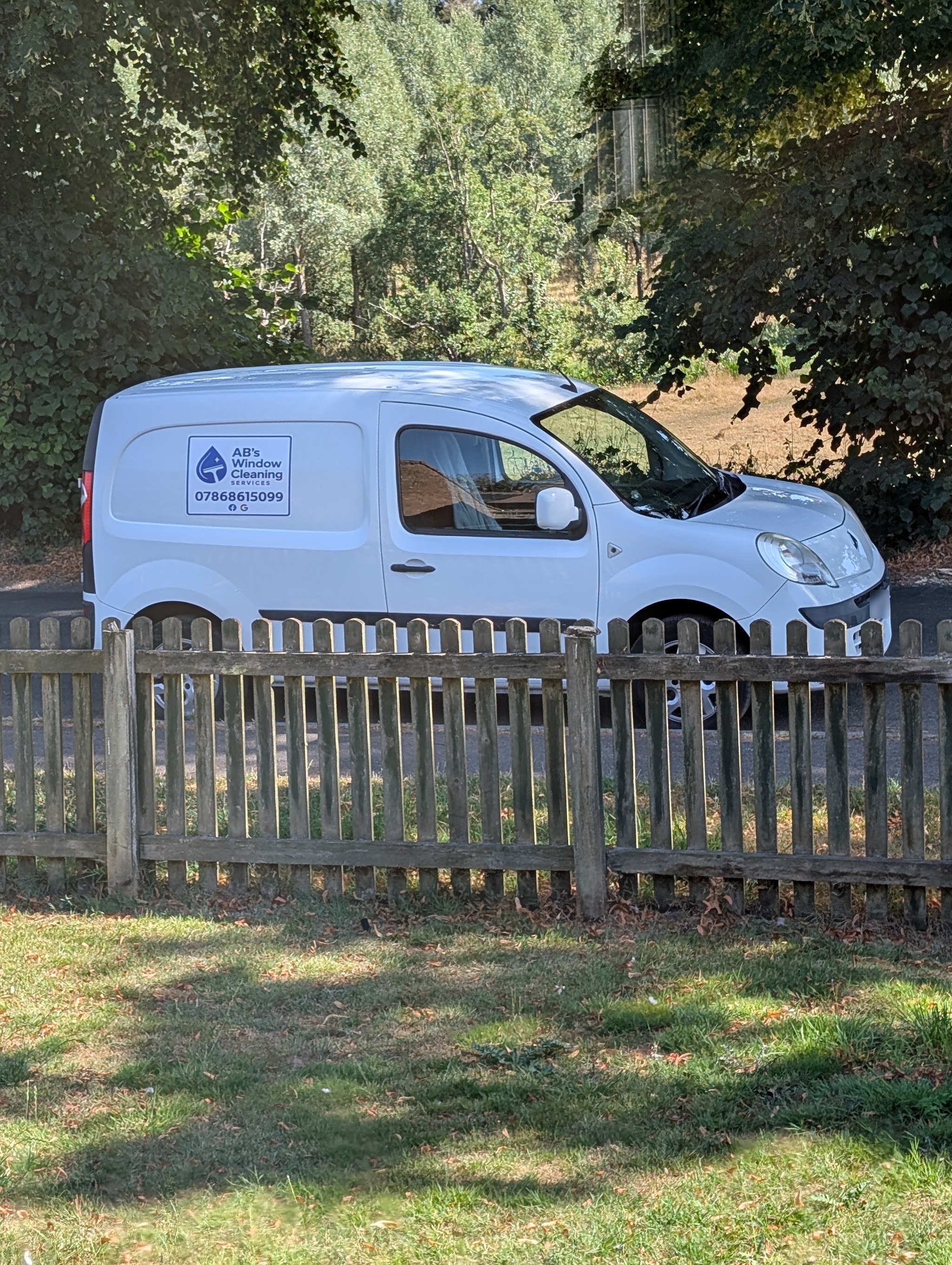 The AB's Window Cleaning van parked behind a wooden picket fence