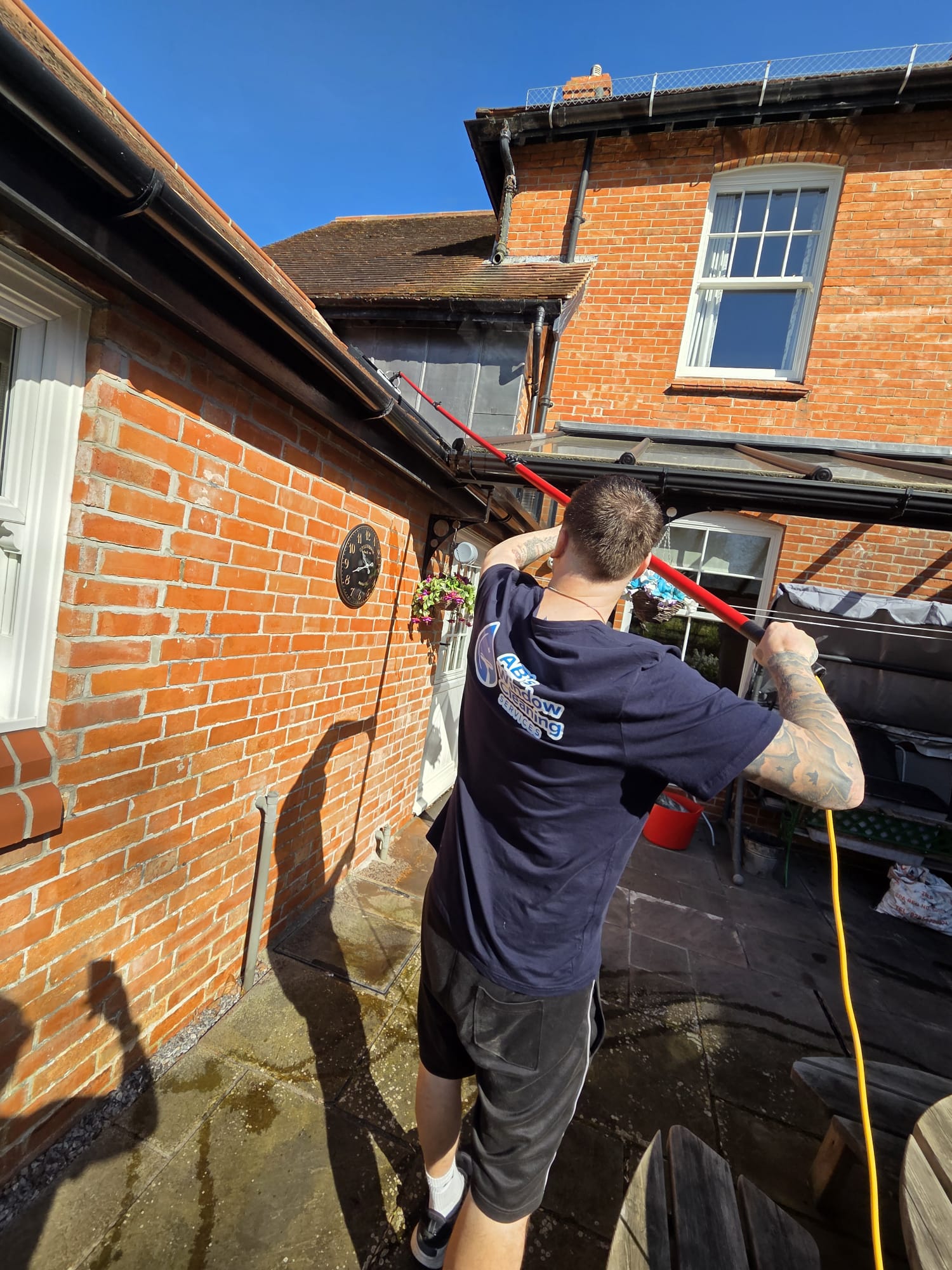 Cleaning with the water-fed pole on a red-brick house