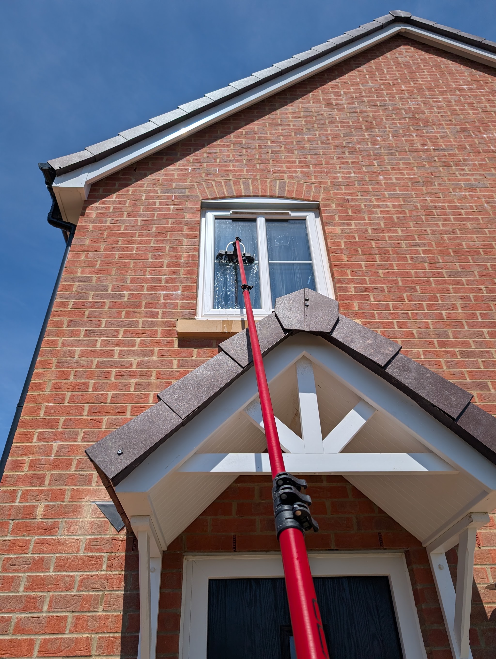 The water-fed pole at an upstairs window above a porch on a red-brick new build