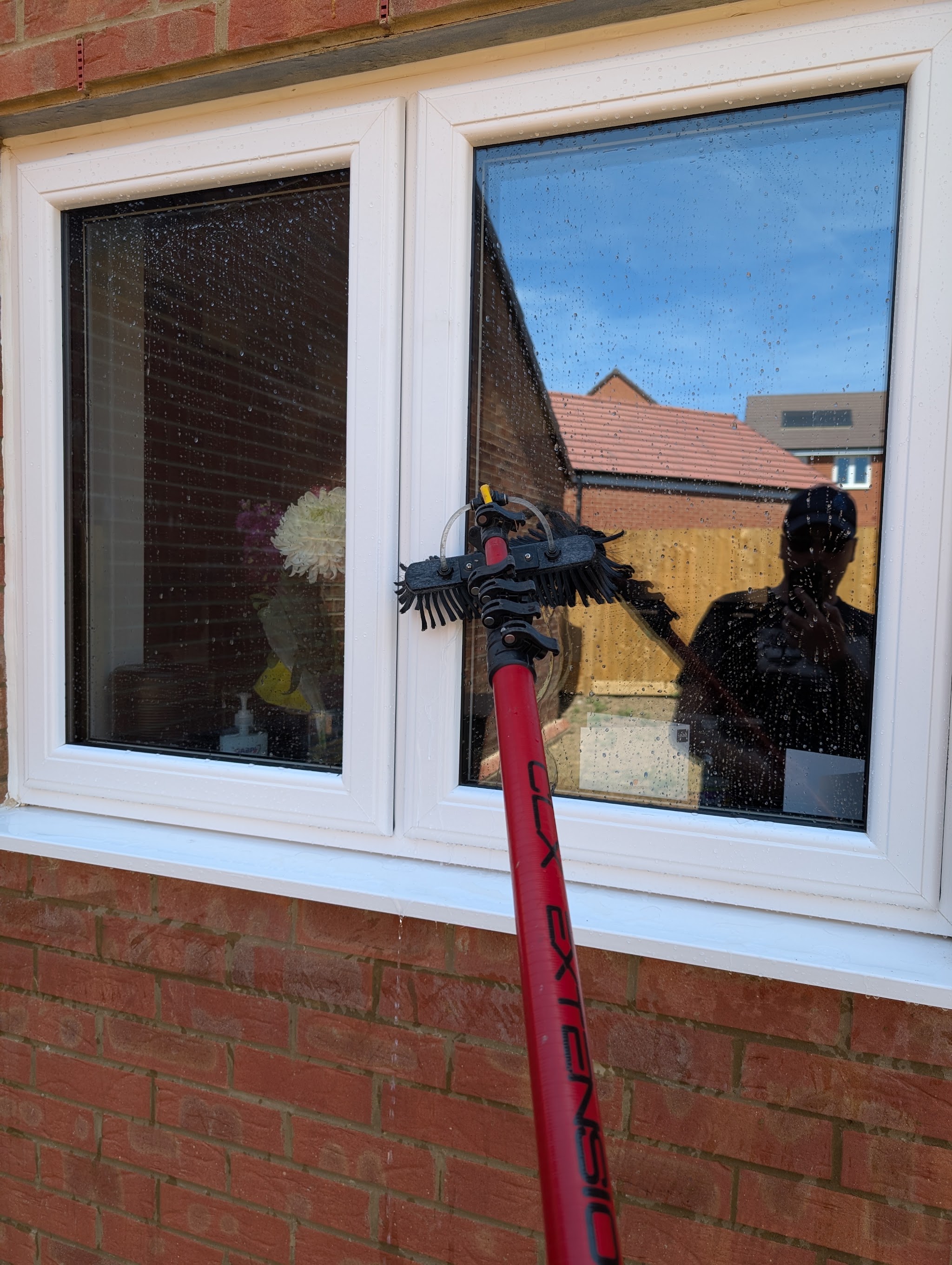 Close-up of the pole brush working on a white uPVC window